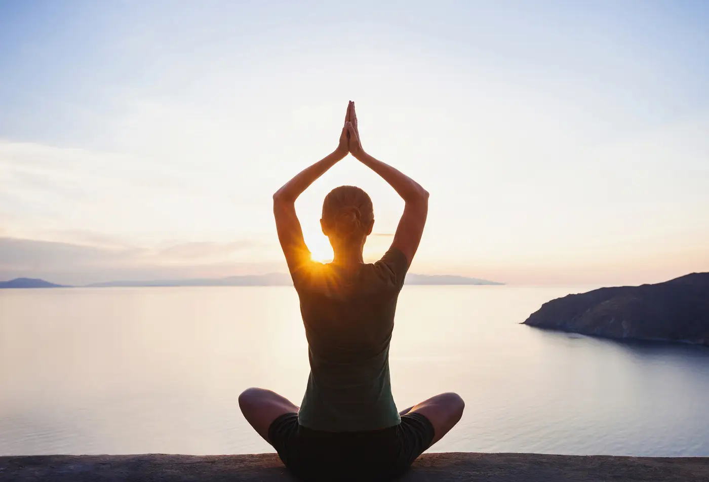 Young woman practicing yoga near the sea at sunset. Harmony, med